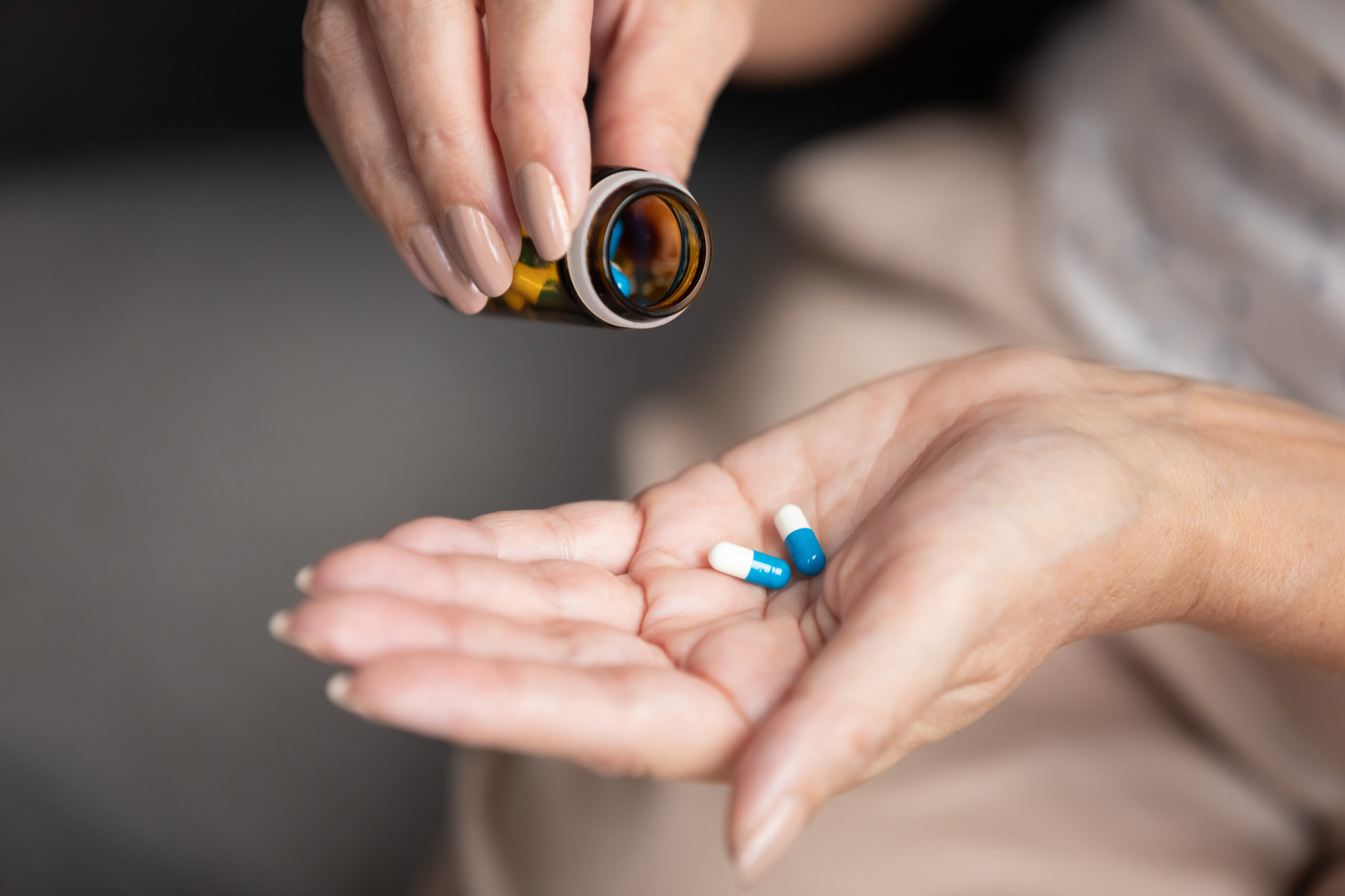 Closeup view elderly female holding two pills taking daily dosage